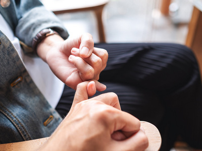 Image of man and a woman hooking each other little finger.